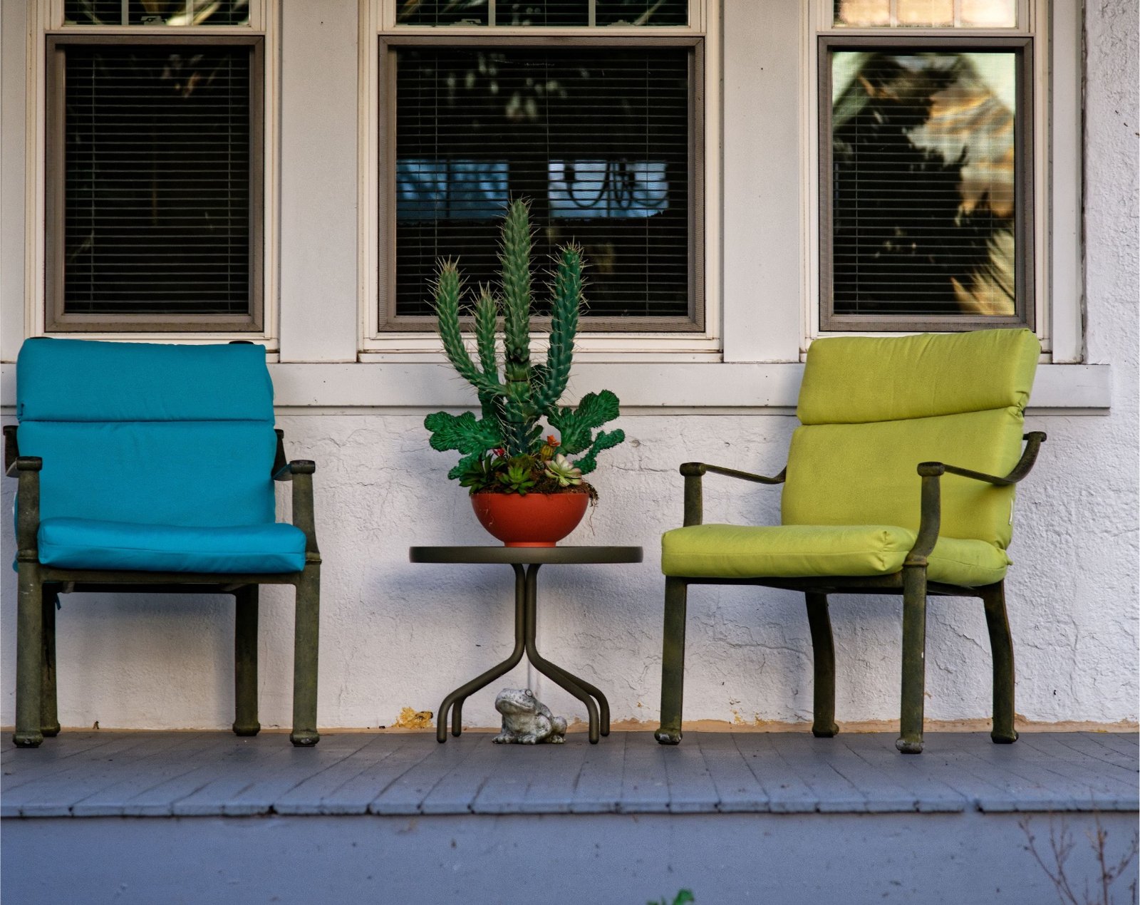 Twee stoelen met een cactus ertussen op een veranda